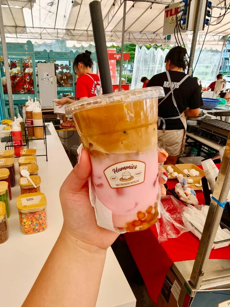 Hand holding a pink dalgona drink at an event