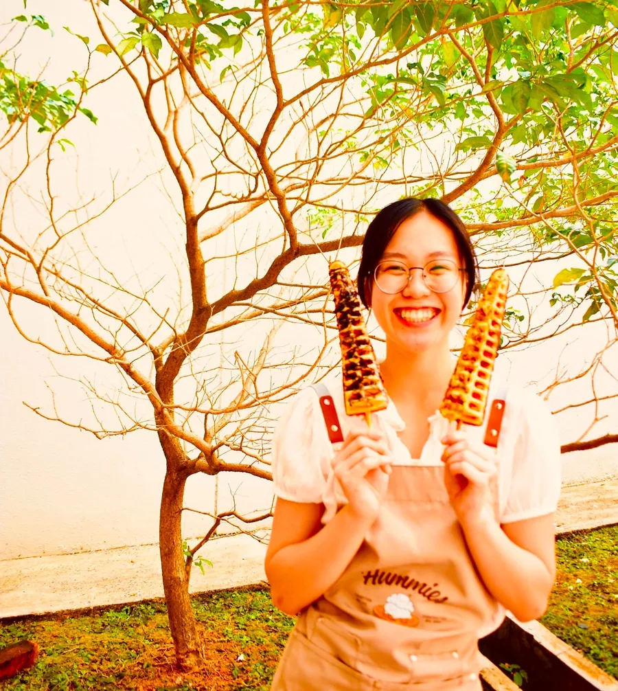 Carol holding two waffle wands in a park